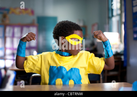 African American boy wearing superhero costume in classroom Banque D'Images