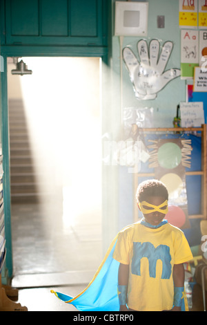 African American boy wearing superhero costume in classroom Banque D'Images