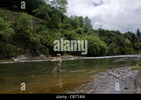 Un pêcheur de mouche bénéficie de l'action de la truite sur une magnifique petite rivière de la Nouvelle-Zélande dans la région du lac Taupo sur l'Île du Nord Banque D'Images