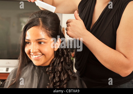 Hispanic woman having hair styled in salon Banque D'Images