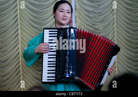 Serveuse de la Corée du Nord joue un accordéon traditionnel au cours de la performance de la Corée du Nord, Pyongyang Restaurant, Phnom Penh, Cambodge. crédit : Kraig Lieb Banque D'Images