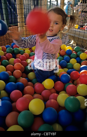 Jeune fille (2 ans) à l'aide d'un lancer des boules en plastique de couleur à l'appareil photo. M. Banque D'Images