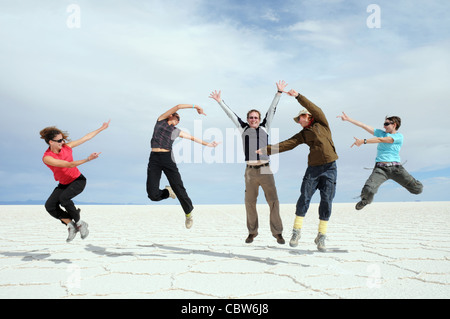 Quatre filles sautant en l'air en haut et en montrant un homme de Bolivie Salar de Uyuni Banque D'Images