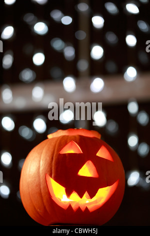 Coupe de main Halloween citrouille avec triangle yeux et dents et la bougie à l'intérieur lumineux, feux de grin spooky montrant en arrière-plan Banque D'Images