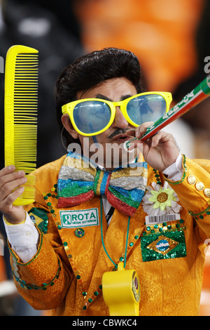 En costume d'un supporter le Brésil affiche un grand sabot et lunettes lors d'un match de Coupe du Monde 2010 entre le Brésil et la Côte d'Ivoire. Banque D'Images