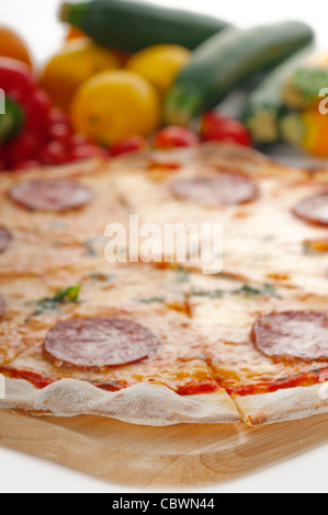 D'origine italienne pizza au pepperoni à croûte mince avec des légumes frais en arrière-plan Banque D'Images