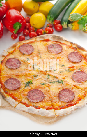 D'origine italienne pizza au pepperoni à croûte mince avec des légumes frais en arrière-plan Banque D'Images