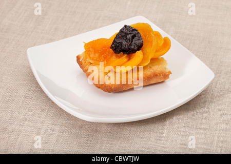 Une partie de tarte aux fruits maison abricot et prune sur une plaque carrée blanche nappe contre Banque D'Images