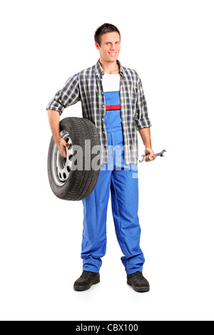 Portrait d'un mécanicien tenant une roue de secours et la tenue d'une clé Banque D'Images