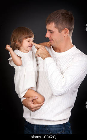 Papa joue avec sa fille sur un fond noir Banque D'Images