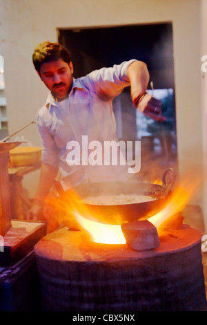 Le café au bord de la marmite en remuant chef curry ragoût dans un wok sur une plaque de cuisson dans tandoori Banque D'Images