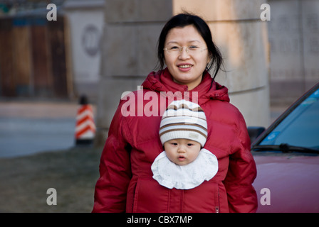 Beijing, Maizidian. Mère portant son bébé dans un style kangourou Banque D'Images