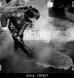 DongBaXiang, Beijing. Jeune homme travaillant dans une usine de recyclage de l'huile de cuisson. Banque D'Images