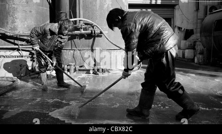 DongBaXiang, Beijing. Les jeunes hommes travaillant dans une usine de recyclage de l'huile de cuisson. Banque D'Images