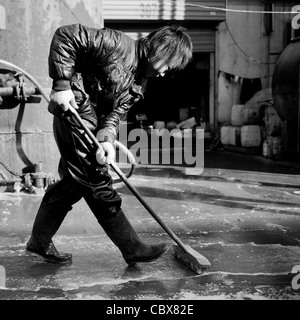 DongBaXiang, Beijing. Jeune homme travaillant dans une usine de recyclage de l'huile de cuisson. Banque D'Images