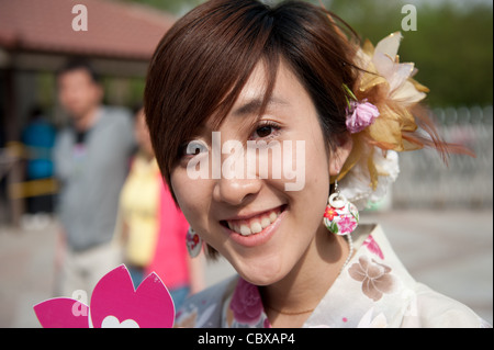 Beijing, Parc Yuyuantan (Jade Lake Park). Femme portant une fleur et autres décorations liées au printemps. Banque D'Images