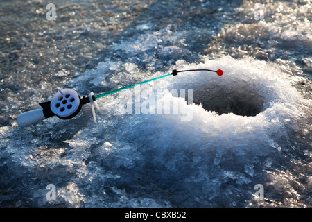 Peu de canne à pêche d'hiver dans le trou Banque D'Images