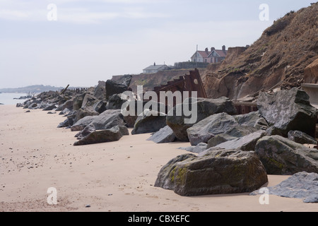 Littoral Happisburgh, North Norfolk, l'East Anglia. L'érosion des falaises de la mer du Nord ; les maisons, à côté du rendez-vous. Les roches importées comme la défense de la mer d'atténuation. Banque D'Images