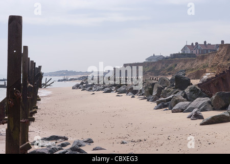 Littoral Happisburgh, North Norfolk, l'East Anglia. L'érosion des falaises de la mer du Nord ; maisons de village, à côté du rendez-vous. Le bois endommagé défenses, à gauche. Banque D'Images