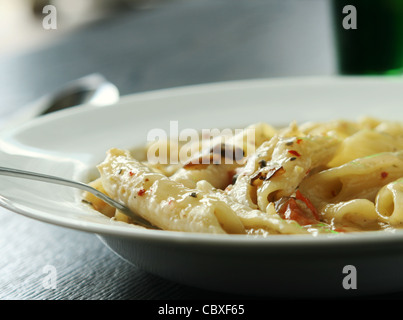 Close up detail shot de pâtes penne servi sur un plat profond plaque en céramique. Une fourchette est mis sur le plat. Banque D'Images