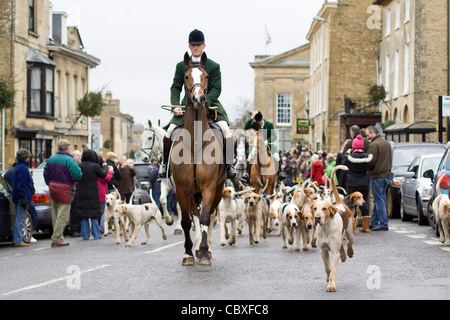 Fox Hounds menée par le village de Chipping Norton par le maître de la chasse sur un cheval pour le boxing day rencontrez Banque D'Images