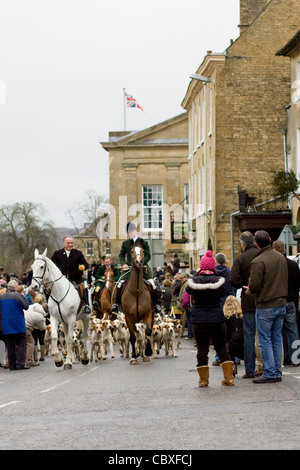 Fox Hounds menée par le village de Chipping Norton par le maître de la chasse sur un cheval pour le boxing day rencontrez Banque D'Images