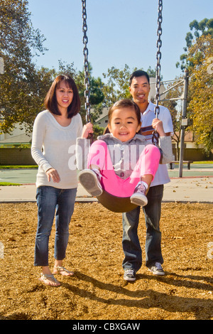 Un Filipino-American Vietnamese-American père, son épouse et leur mélange racial quatre-année-vieille fille visiter une aire de jeux. Banque D'Images