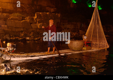 Pêcheur chinois regardant des aigrettes pêcher de nuit sur la rivière Li Yangshuo en République populaire de Chine Banque D'Images