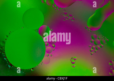 L'huile et l'eau avec un fond vert et violet. Banque D'Images