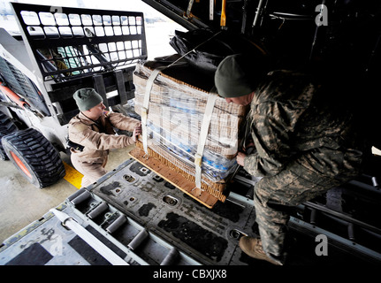 Sgt. Maître Clay Holt aide le sergent de l'Armée de terre. Matthew Davenport charge un Hercules C-130 avec des lots de réapprovisionnement à faible coût et à faible altitude le 6 février 2010, en Afghanistan. Le Sergent Holt est chargé de mission au 774e Escadron de transport aérien expéditionnaire de Bagram, en Afghanistan. Le Sergent Davenport est un NCO à charge externe affecté à la Force opérationnelle interarmées opérationnelle interarmées en Afghanistan. Banque D'Images