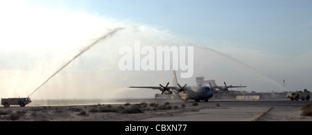 C-130 Hercules no 1847 traverse le jet d'eau cérémonial de deux camions d'incendie dans une base aérienne en Asie du Sud-Ouest après avoir terminé sa mission finale de combat le 28 janvier. Après 47 ans de service, l'avion est à la retraite. Banque D'Images