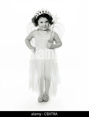 Photo en studio monochrome à clé élevée d'un jeune enfant du caucase vêtu d'un costume de fée avec des ailes et une baguette. Banque D'Images