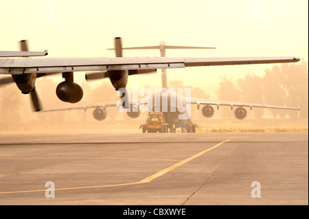 Prenant la poussière dans la foulée, un C-130 Hercules se prépare à sortir de taxi le 31 juillet par un C-17 Globemaster III est chargé avec sa cargaison à base d'diamondback à Mossoul, en Irak. Banque D'Images