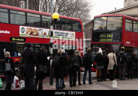 Une file de gens qui attendent à bord d'un bus rouge de Londres Banque D'Images