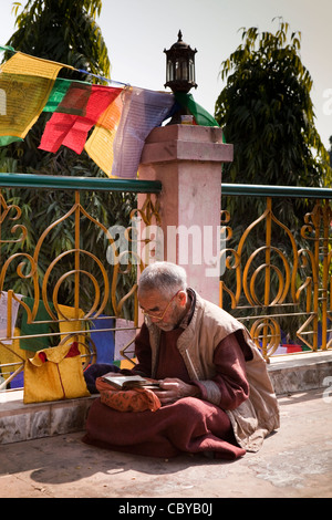 L'Inde, le Bihar, le Temple de la Mahabodhi Bodhgaya, bouddhiste, un moine en prière au-dessous colouful les drapeaux de prières Banque D'Images