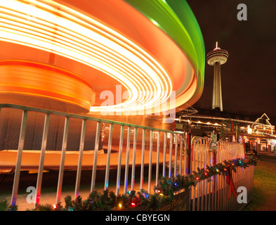 Tourner manège carrousel durant la saison de Noël à Niagara Falls avec la tour Skylon en arrière-plan. L'Ontario, Canada Banque D'Images