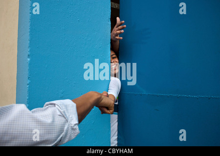 Le président Barack Obama se rend dans la rue à l'onde pour les gens se sont réunis à l'extérieur de la Cidade de Deus favela Community Centre 20 mars 2011 à Rio de Janeiro, Brésil. Alors qu'il marchait, un jeune garçon atteint d'une porte fermée et le Président atteint plus de lui donner un coup de poing. Banque D'Images