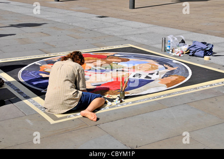 Scène de rue vue arrière de l'artiste qui travaille sur la création d'art sur les dalles de la chaussée dans la zone touristique à Trafalgar Square London England UK Banque D'Images