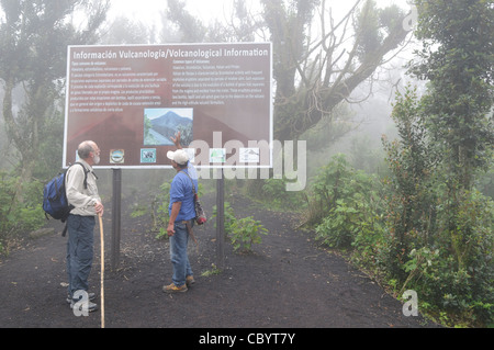 VOLCAN PACAYA, Guatemala — un des guides touristiques locaux fournit des informations à un randonneur près du sommet du volcan Pacaya par un matin brumeux. Pacaya est un volcan actif qui fait partie de l'Arc volcanique d'Amérique centrale. Il forme une destination touristique populaire facilement accessible depuis Antigua et Guatemala City. Situé dans le parc national de Pacaya, il culmine à 2 552 mètres (8 373 pieds). Sa dernière éruption majeure, qui a causé un damange considérable aux villages voisins et remodelé le sommet, a eu lieu en mai 2010. Cette éruption et les cendres volcaniques dispersées sur une grande partie de la zone voisine, incitant l'école Banque D'Images