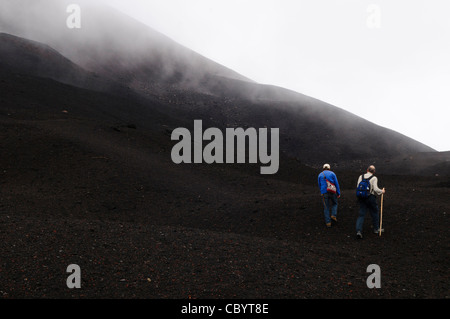 VOLCAN PACAYA, Guatemala — guide et randonneur au sommet du volcan Pacaya. Pacaya est un volcan actif qui fait partie de l'Arc volcanique d'Amérique centrale. Il forme une destination touristique populaire facilement accessible depuis Antigua et Guatemala City. Situé dans le parc national de Pacaya, il culmine à 2 552 mètres (8 373 pieds). Sa dernière éruption majeure, qui a causé un damange considérable aux villages voisins et remodelé le sommet, a eu lieu en mai 2010. Cette éruption et les cendres volcaniques dispersées sur une grande partie de la zone voisine, provoquant des fermetures d'écoles et des évacuations d'urgence et nettoyant une grande partie du vege Banque D'Images