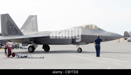 Le principal Airman Dez Watson salue un F-22 Raptor qui se rend en taxi vers la piste le 6 août 2010, à la base aérienne de Mountain Home, Idaho. Plus de 150 aviateurs et 12 F-22 du 43e Escadron de chasseurs de la base aérienne de Tyndall (Floride) sont arrivés le 31 juillet 2010, à l'appui du premier entraînement conjoint de la Force aérienne sur le Global Gem. Airman Watson est un chef d'équipage de la 43e unité de maintenance d'aéronef. Banque D'Images