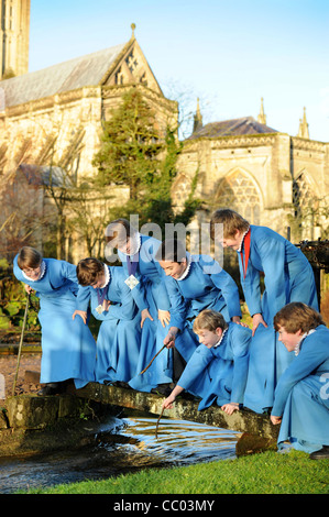 Les choristes du garçon Wells Cathedral Choir dans Somerset UK de prendre une pause de jouer les répétitions par 'le' Puits étang après whic Banque D'Images