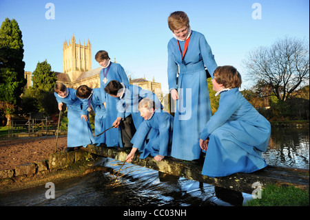 Les choristes du garçon Wells Cathedral Choir dans Somerset UK de prendre une pause de jouer les répétitions par 'le' Puits étang après whic Banque D'Images