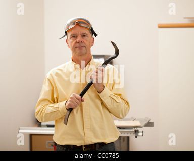 Senior male dans un atelier d'accueil face à l'objectif et la tenue d'une biche Banque D'Images