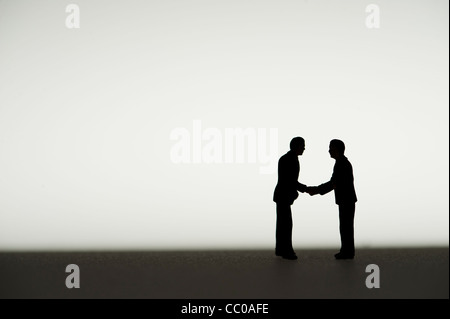 La silhouette de petites figures conceptual image pour deux hommes d'affaires d'accord rencontre un accord shaking hands Banque D'Images