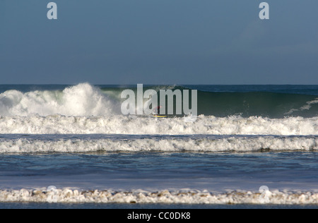 Un surfeur sur une grosse vague à Porthtowan beach, Cornwall. Banque D'Images