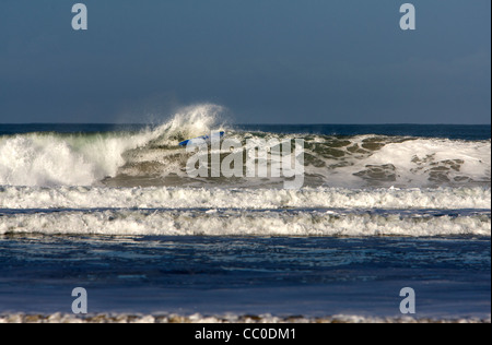 Un surfer efface sur une grosse vague à Porthtowan beach, Cornwall. Banque D'Images