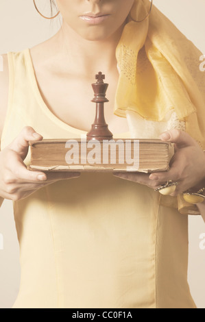 Femme tenant un vieux livre d'échecs et des roi morceau Banque D'Images