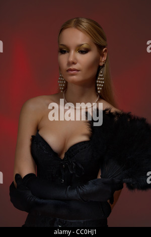 Gorgeous woman à la partie qui a l'air pensif article holding feather fan Banque D'Images