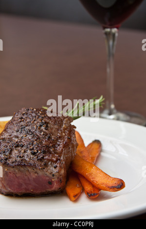 En croûte au poivre Tournedos de boeuf sur les pommes de terre dauphinois et sherry-carottes glacées Banque D'Images